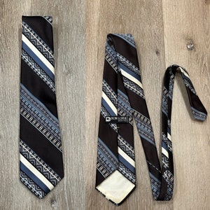 May include: A black and white patterned tie with a blue and white stripe design. The tie has a label that reads "DON LOPER" and is made of a silky material.