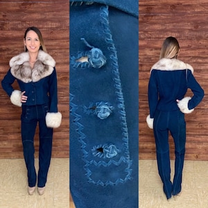 May include: A blue suede pantsuit with a fur collar and cuffs. The jacket has three decorative buttons with knotted details. The pants have a high waist and a straight leg.