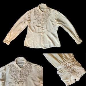 May include: A vintage cream-colored blouse with long sleeves and a mandarin collar. The blouse features delicate lace detailing around the collar and cuffs.