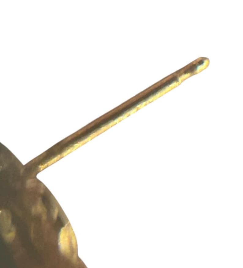 May include: Close-up of a gold-colored earring post. The post is a thin, straight rod with a rounded tip. The earring post is set against a white background.