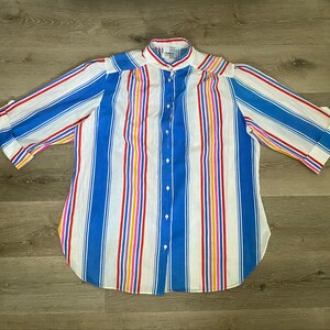 May include: A white button-down shirt with blue, red, yellow, and pink stripes. The shirt has a mandarin collar and three-quarter sleeves.