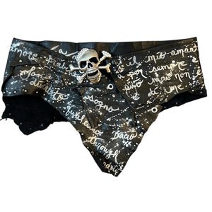 Puede incluir: Cinturón de cuero negro con hebilla de calavera y huesos cruzados plateada. El cinturón está adornado con salpicaduras de pintura blanca y escritura a mano. Diseño único y atrevido.
