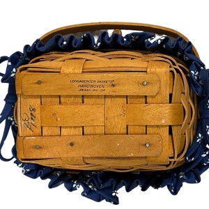 May include: A Longaberger Baskets handwoven basket with a blue and white fabric liner. The basket has a label that reads "Longaberger Baskets Handwoven  Dresden, Ohio USA".