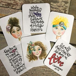 May include: Set of six illustrated coasters with inspirational quotes and bible verses. Each coaster features a watercolor illustration of a woman with a different expression and a flower crown. The quotes include "Restore to me the joy of your salvation", "Surely goodness and mercy shall follow me all the days of my life", "Let all that you do be done in love", "Faith", "Thanks", and "Grow".