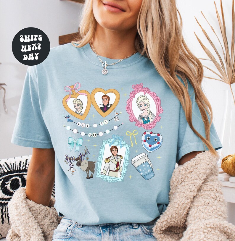 A woman wearing a light blue t-shirt with various cartoon characters and designs printed on it.