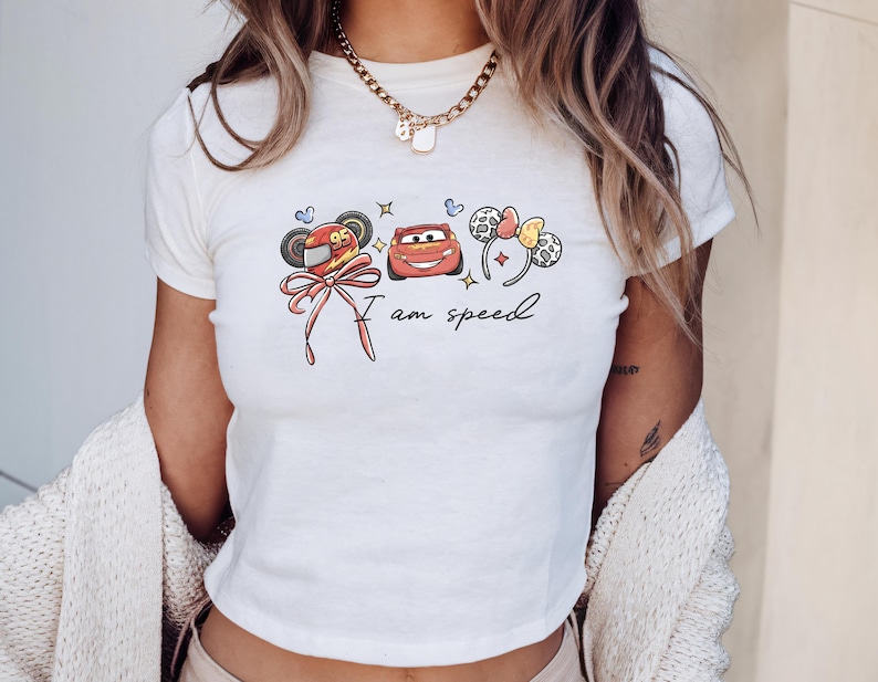 A woman wearing a white t-shirt with a graphic design featuring cartoon characters and the text "I am speed".