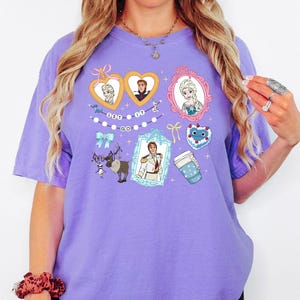 A woman wearing a purple t-shirt with various cartoon characters and designs printed on it.