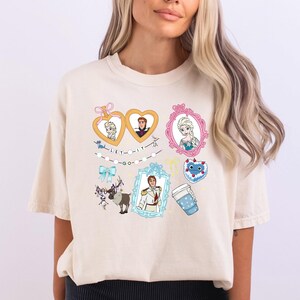 A woman wearing a white t-shirt with various cartoon-style illustrations and characters on it.