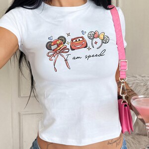 A person wearing a white t-shirt with a graphic design and holding a pink drink.