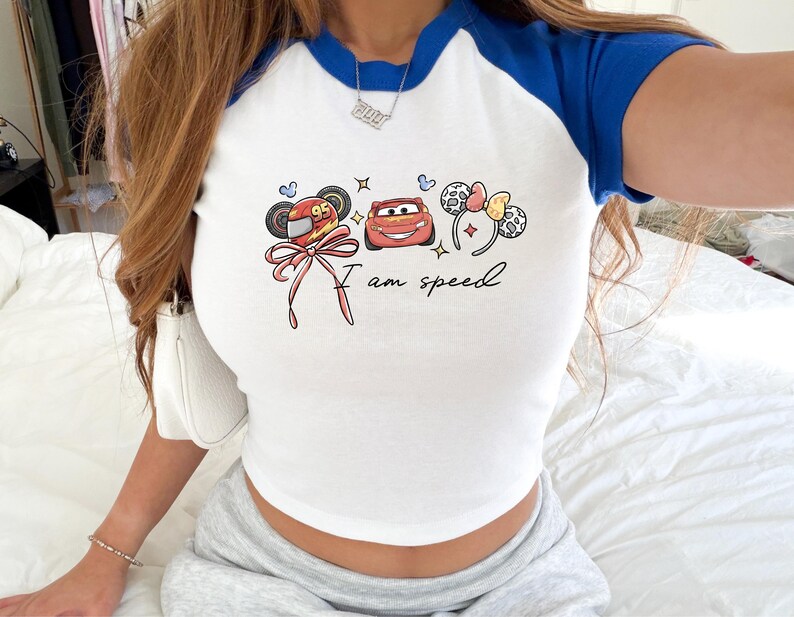 A person wearing a white and blue shirt with a graphic design featuring cartoon characters and the text "I am speed".