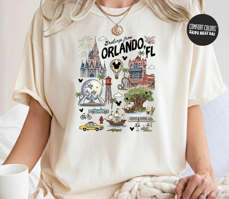 A person wearing a white t-shirt with a graphic design depicting various landmarks and attractions in Orlando, Florida.