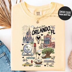 A yellow t-shirt with a colorful graphic design depicting various landmarks and icons associated with Orlando, Florida, such as Disney World, the Walt Disney World Resort, and palm trees.