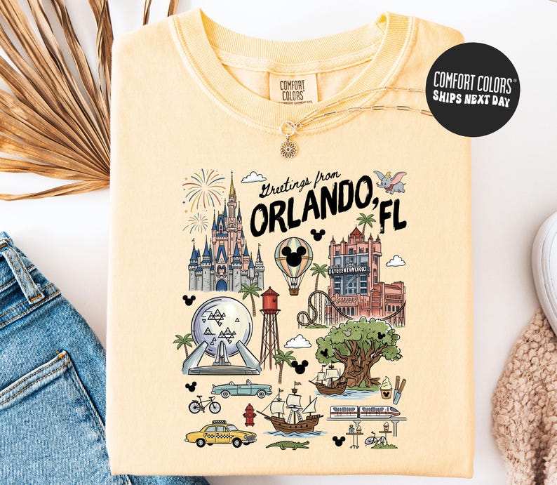 A yellow t-shirt with a colorful graphic design depicting various landmarks and icons associated with Orlando, Florida, such as Disney World, the Walt Disney World Resort, and palm trees.