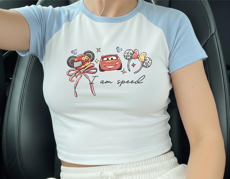 A person wearing a white t-shirt with a graphic design featuring cartoon characters and the text "I am speed".