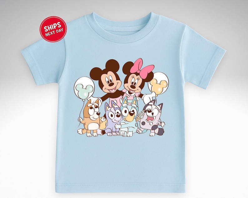 A light blue t-shirt with a cartoon image of various Disney characters, including Mickey Mouse, Minnie Mouse, Bluey the Cat, and other iconic figures.