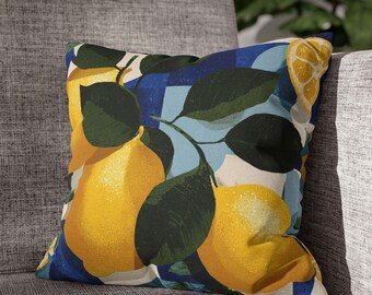 May include: Square throw pillow with a lemon design. The pillow features large yellow lemons with green leaves against a blue and white patterned background. The pillow is placed on a gray upholstered chair.