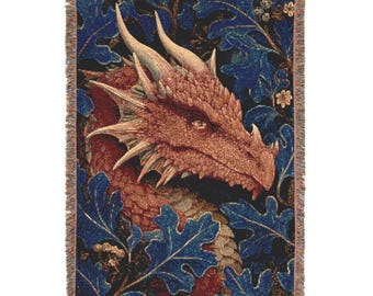 Puede incluir: Manta tejida con un diseño de cabeza de dragón detallada en tonos rojos, marrones y beige. El dragón está rodeado de hojas de roble azules y detalles florales sobre un fondo oscuro. La manta tiene un borde con flecos.