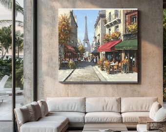Puede incluir: Una gran pintura cuadrada representa una escena callejera parisina con la Torre Eiffel al fondo. La obra de arte presenta edificios con toldos rojos y verdes, una calle adoquinada y figuras. La pintura se exhibe sobre un sofá seccional de color claro en una sala de estar moderna.