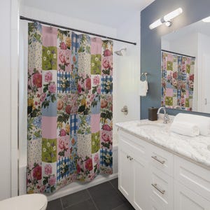 Peut inclure: Rideau de douche patchwork à motifs floraux roses, bleus, verts et blancs. Le rideau présente divers motifs floraux et des carrés vichy. Il est suspendu dans une salle de bain aux murs blancs et au sol sombre.