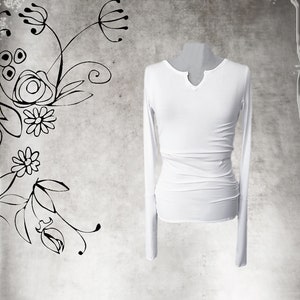 May include: A white long-sleeved shirt with a V-neckline. The shirt is made of a soft, stretchy fabric and has a fitted silhouette.