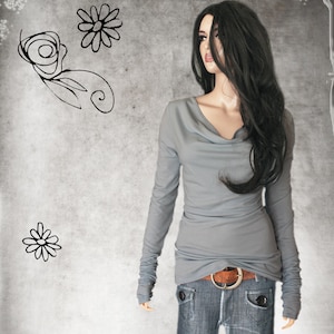 May include: A gray long-sleeved shirt with a cowl neck and a brown belt. The shirt is made of a soft, stretchy fabric and has a relaxed fit.