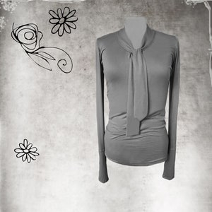 May include: A gray long-sleeved shirt with a tie at the neck.