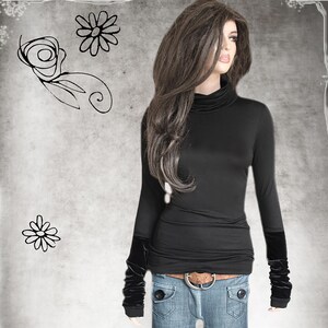 May include: A black long-sleeved shirt with a mock neck and velvet cuffs. The shirt is tucked into blue jeans with a brown belt.