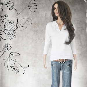 May include: A white long-sleeved shirt with a collared neckline and a v-shaped opening. The shirt is tucked into a pair of blue jeans with a brown belt.