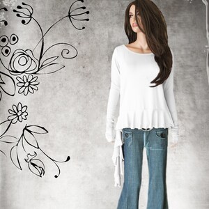 May include: A white long-sleeve top with a ruffled hem and flared jeans. The jeans have front pockets and a belt. The mannequin has long brown hair.