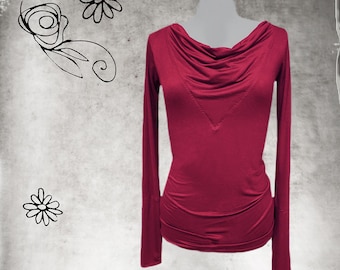 May include: A long-sleeved shirt in a deep burgundy red color featuring a draped cowl neckline and a V-shaped seam detail across the chest. The garment has a fitted silhouette with gathered fabric at the waist and long, slim sleeves.