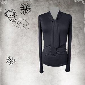 May include: A dark gray long-sleeved shirt with a tie at the neck.