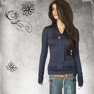 May include: A navy blue long-sleeved shirt with a tie at the neck. The shirt is fitted and has a slightly gathered look at the waist. The model is wearing blue jeans.