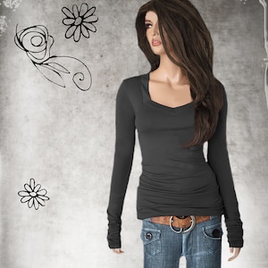 May include: A charcoal gray long-sleeved shirt with a scoop neck and cuffed sleeves. The shirt is fitted and has a slightly gathered look at the waist. The model is wearing the shirt with blue jeans and a brown belt.
