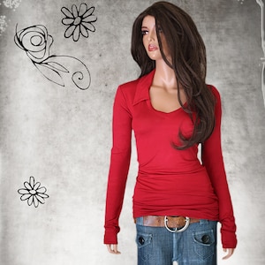 May include: A red long-sleeved shirt with a v-neck collar and a brown belt. The shirt is fitted and has a slightly gathered look.