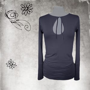 May include: A dark gray long-sleeve top featuring a round neckline with a teardrop-shaped cutout and a tie closure. The garment has fitted sleeves and gathered fabric detailing along the lower sides, providing a textured appearance.
