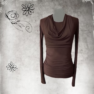 May include: A long-sleeved brown top featuring a draped cowl neckline and a fitted, ruched bodice. The garment has a smooth, solid-colored fabric construction with extended sleeves and a gathered waistline, presenting a clean and structured silhouette.