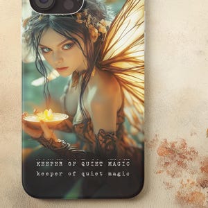 May include: A phone case featuring a fantasy illustration of a fairy with golden wings, holding a glowing object. The case has a black bottom and the text "KEEPER OF QUIET MAGIC" in white.