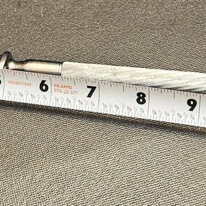 Pu&ograve; includere: Un coltello antico argentato con un manico strutturato, lungo circa 30 cm. Un metro a nastro bianco &egrave; posto accanto al coltello, mostrandone la lunghezza.