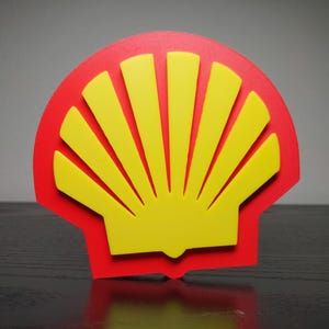 May include: A red and yellow Shell logo, a stylized scallop shell design. The logo features a red outline with a yellow shell shape inside. The image is a close-up shot, highlighting the bright colors and the iconic design.
