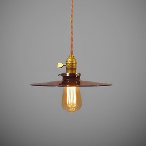 May include: A black metal pendant light with a brown cord and a clear light bulb. The light fixture has a simple, industrial design.