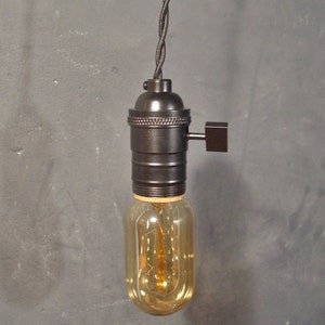 May include: A black pendant light fixture with a clear glass bulb and a black cord. The light fixture has a switch on the side.
