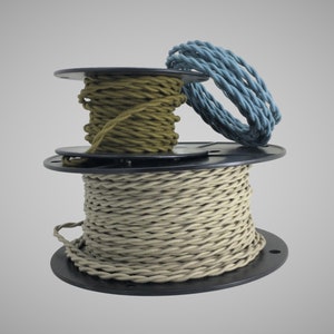 Op de afbeelding: Drie spoelen met gedraaid elektriciteitsdraad, één in teal, één in olijfgroen en één in beige.