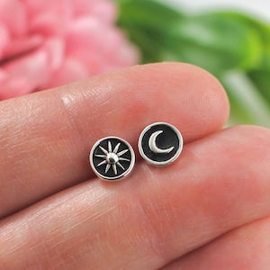 May include: A pair of silver stud earrings with a sun and moon design. The earrings are small and delicate, and they would make a great gift for someone who loves celestial jewelry.