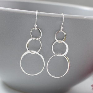 May include: Silver dangle earrings with three interlocking circles.