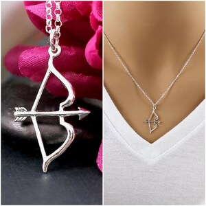 May include: A silver necklace with a bow and arrow pendant. The pendant is a simple design with a heart-shaped bow and a straight arrow.