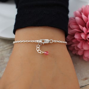 May include: A silver chain bracelet with a small pink crystal charm.