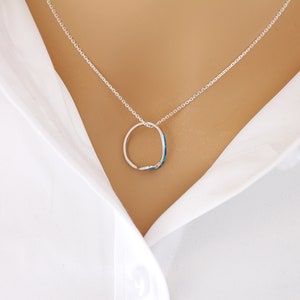 Puede incluir: Un collar de cadena de plata con un colgante redondo con una piedra azul y verde que parece una &oacute;palo.