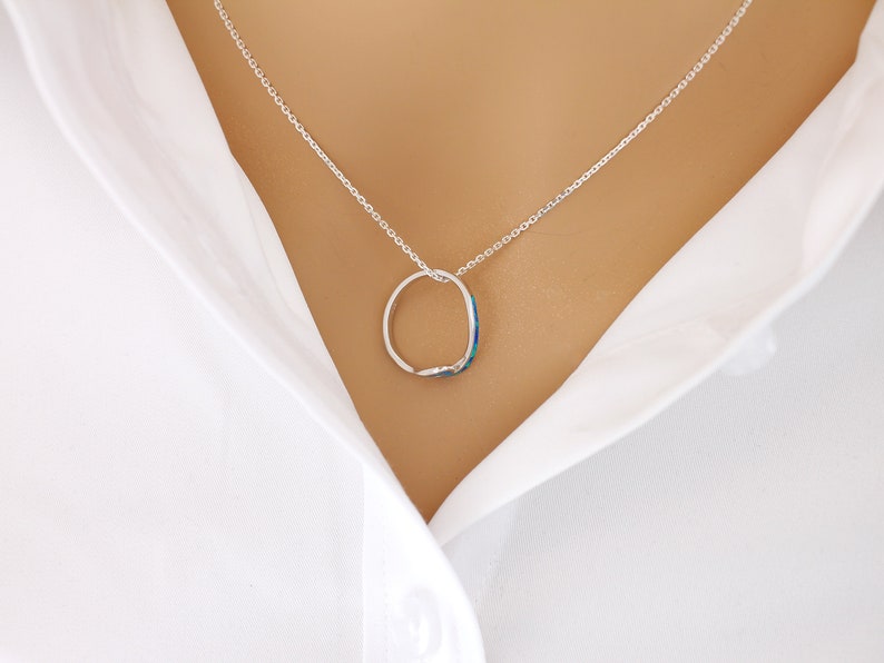 Puede incluir: Un collar de cadena de plata con un colgante redondo con una piedra azul y verde que parece una &oacute;palo.