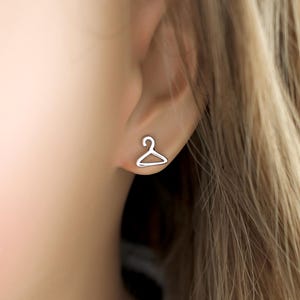 May include: A pair of silver earrings shaped like a hanger.