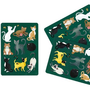 May include: Three rectangular dark green placemats featuring a repeating illustration of various cats in different colors and poses, including white, black, brown, and tabby cats, some playing with pink yarn balls and small yellow butterflies.